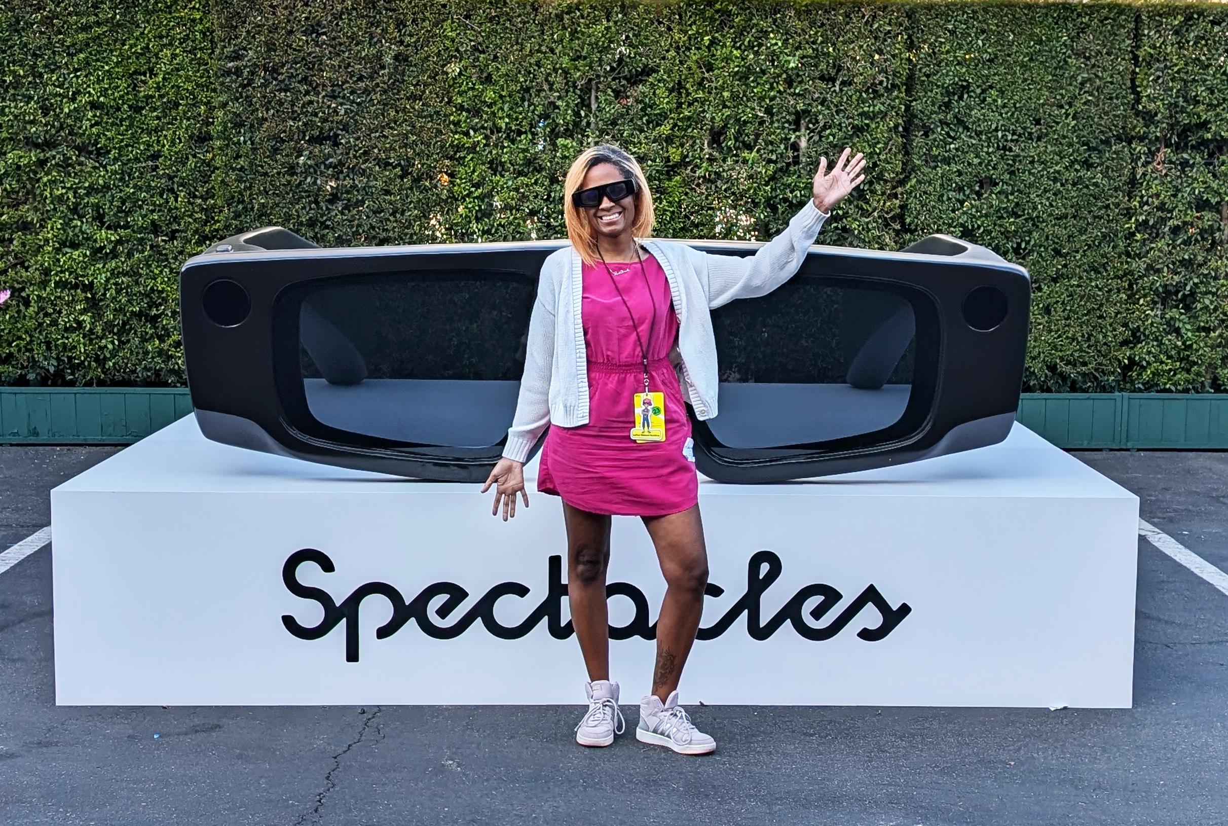A full length photo of me smiling and wearing snapchat spectacles glasses. I'm posing in front of a large replica of the Snapchat spectales.